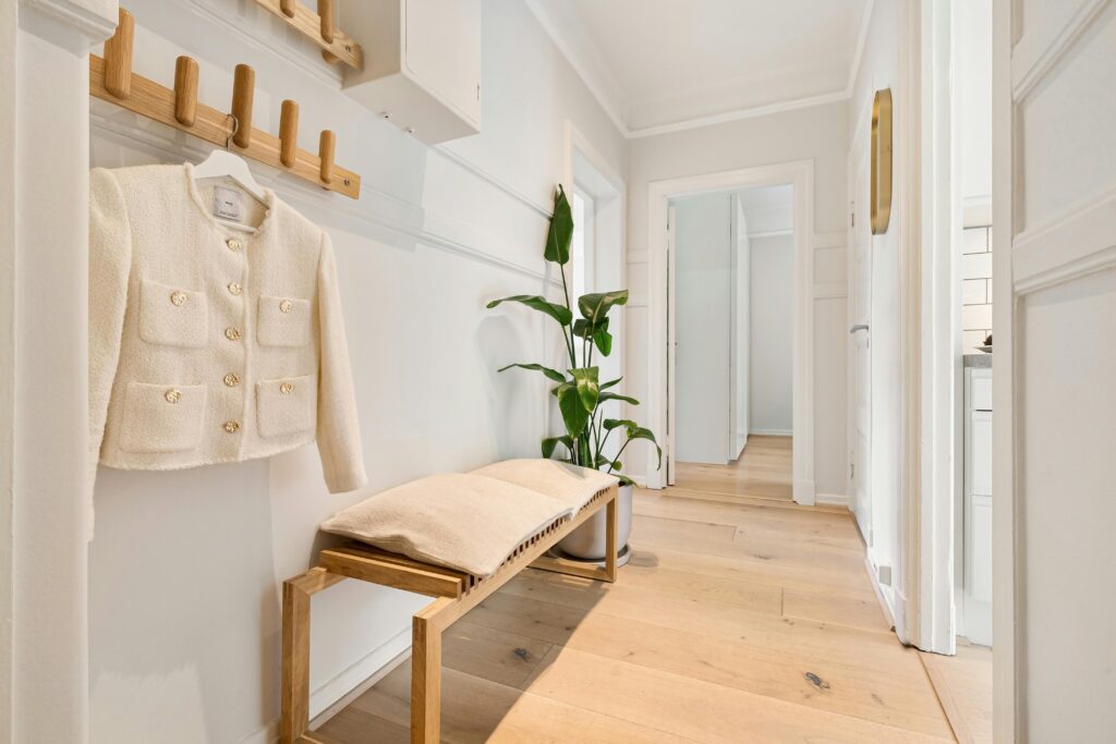 Bright minimalist hallway featuring wooden furniture and a stylish coat rack.