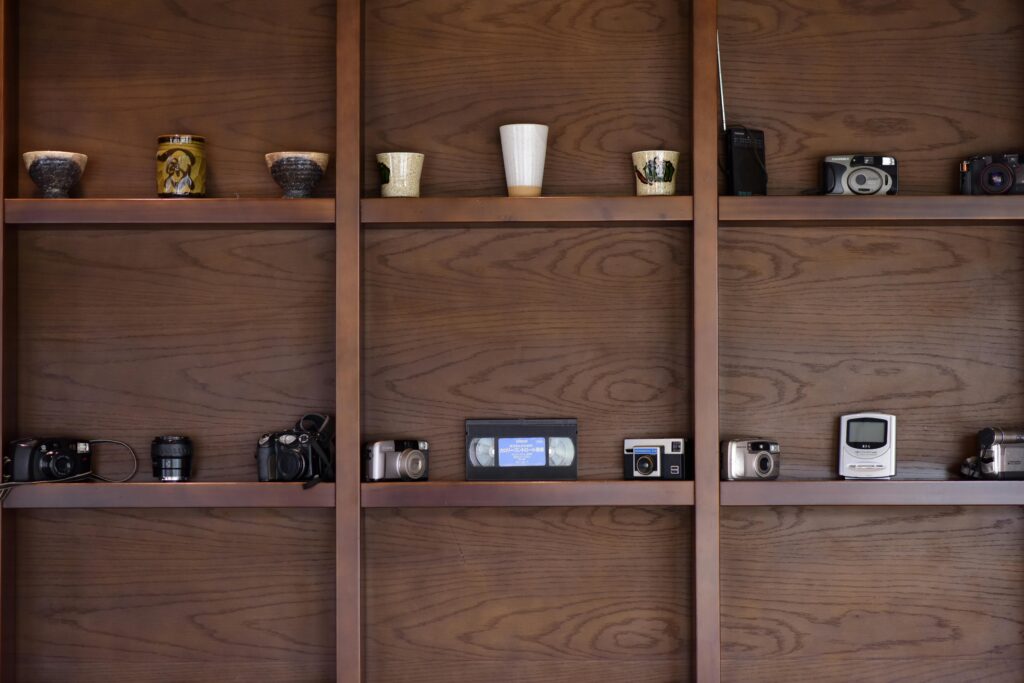 A collection of vintage cameras and decorative items neatly arranged on wooden shelves.