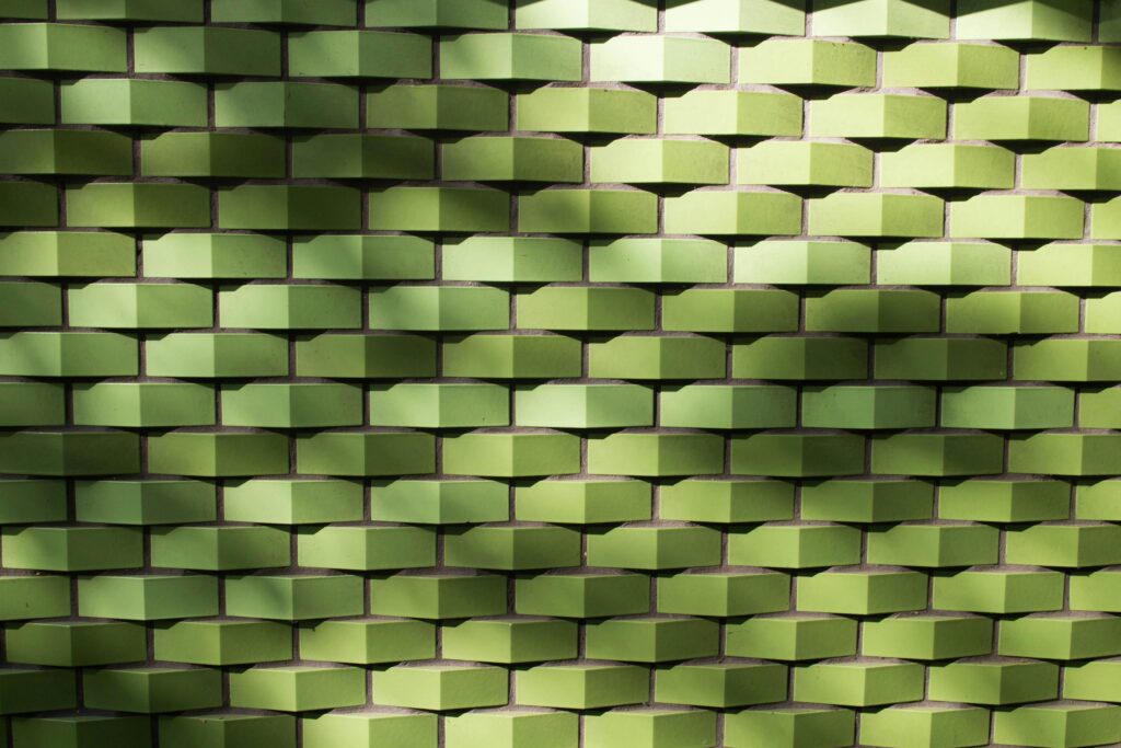 Textured green tile wall with geometric pattern and light shadows, ideal for backgrounds.