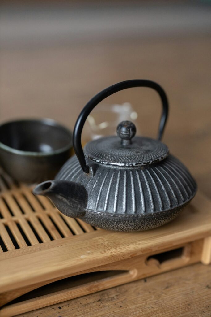 Close-up of a traditional cast iron teapot on a bamboo trivet, perfect for tea ceremonies.