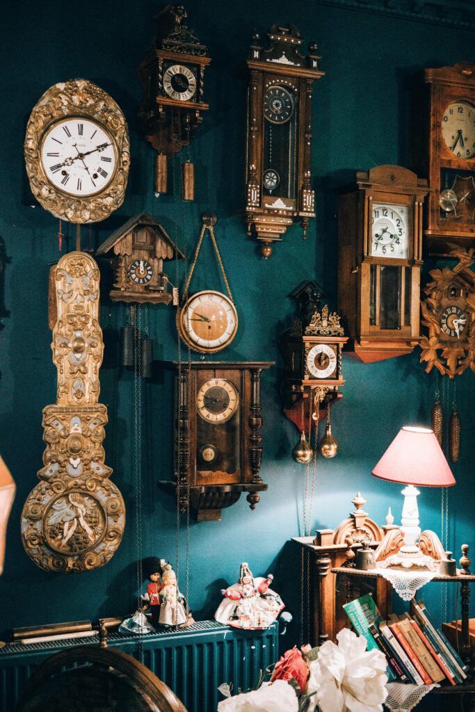 A charming collection of vintage wall clocks on a teal wall in a cozy, warmly lit room.