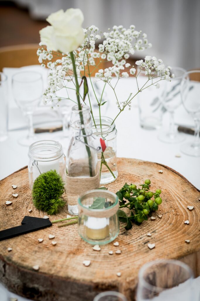 A charming rustic table centerpiece featuring flowers in glass jars on a wooden slab.