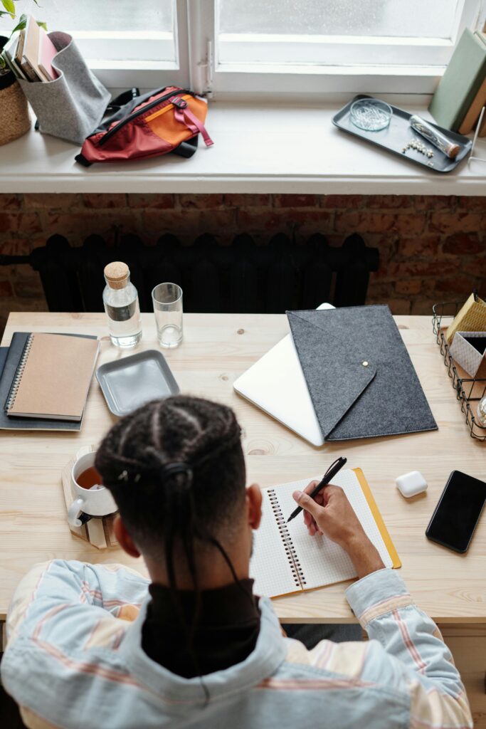 Overhead view of a student studying at a desk with notebooks, phone, and coffee.